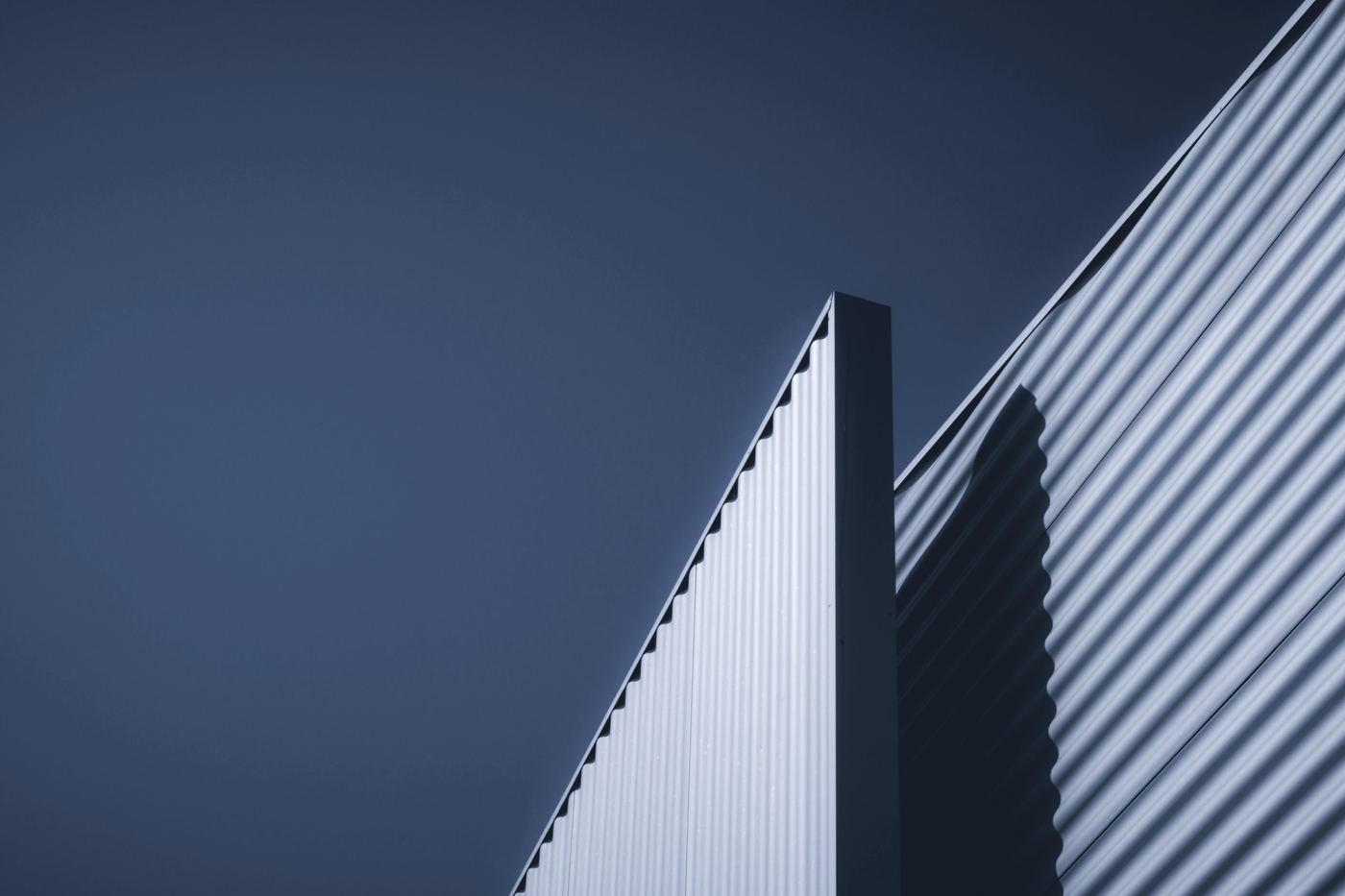 The ribbed metal edge of a modern building against a grey sky