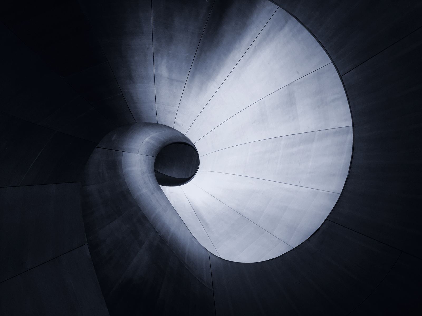 A concrete spiral seen from below, curving into a dark centre